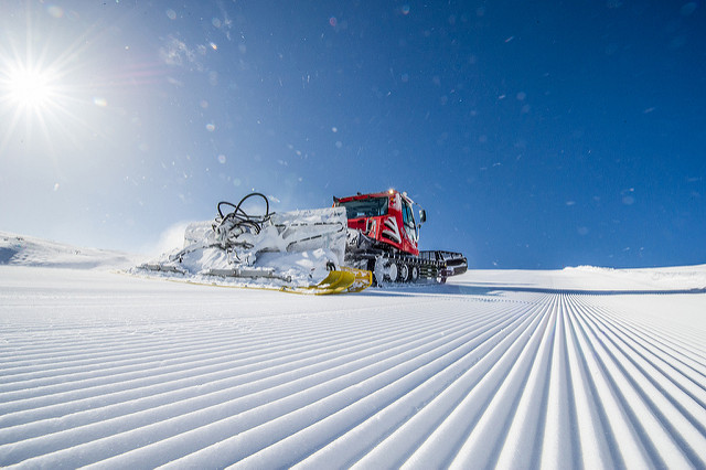 Nypistad backe i Hemsedal skicenter Pistmaskin i strålande sol och klarblå himmel med påstmaskin i arbete